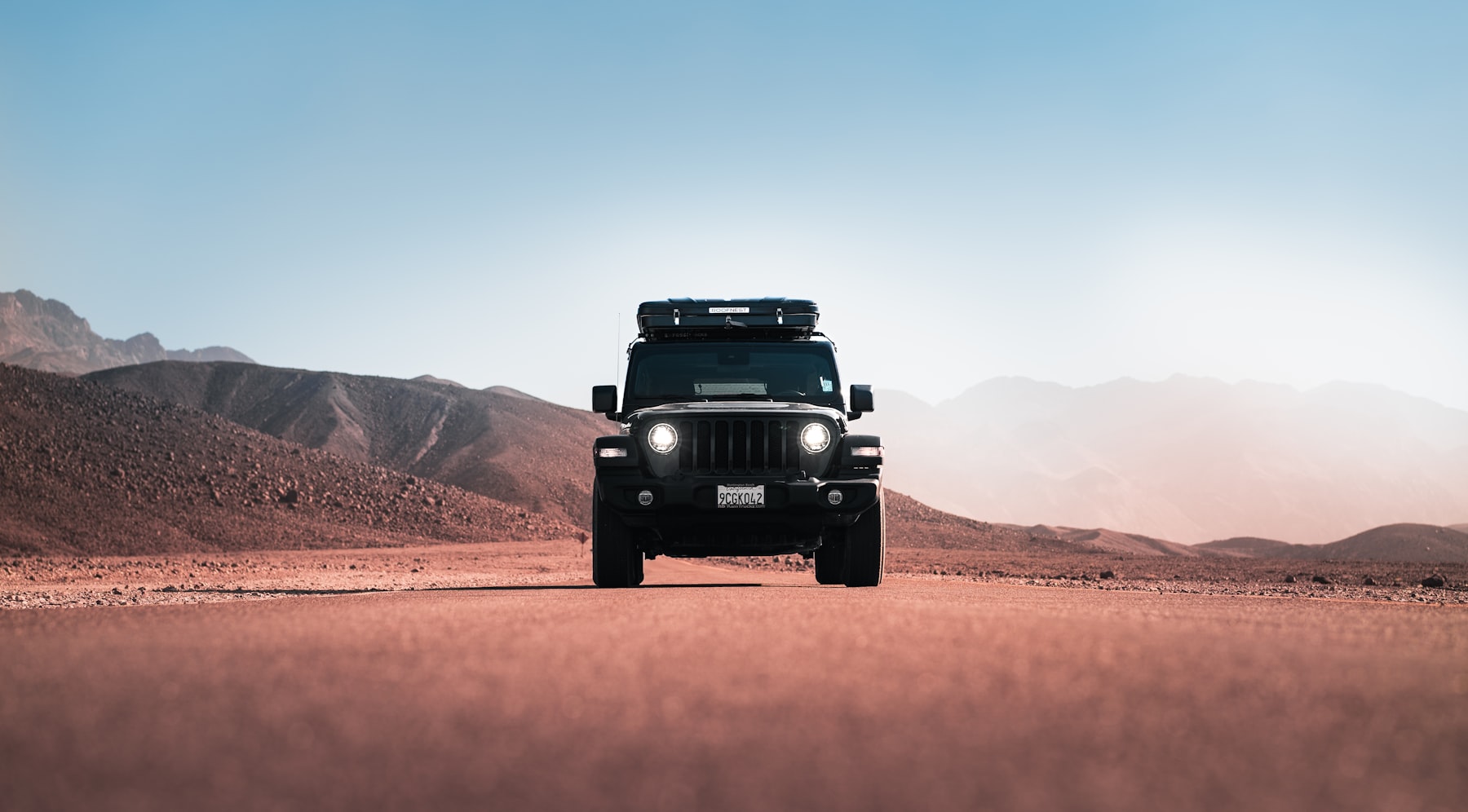 Jeep Wrangler with rooftop tent on desert road, mountain skyline — WrenchLab Offroad